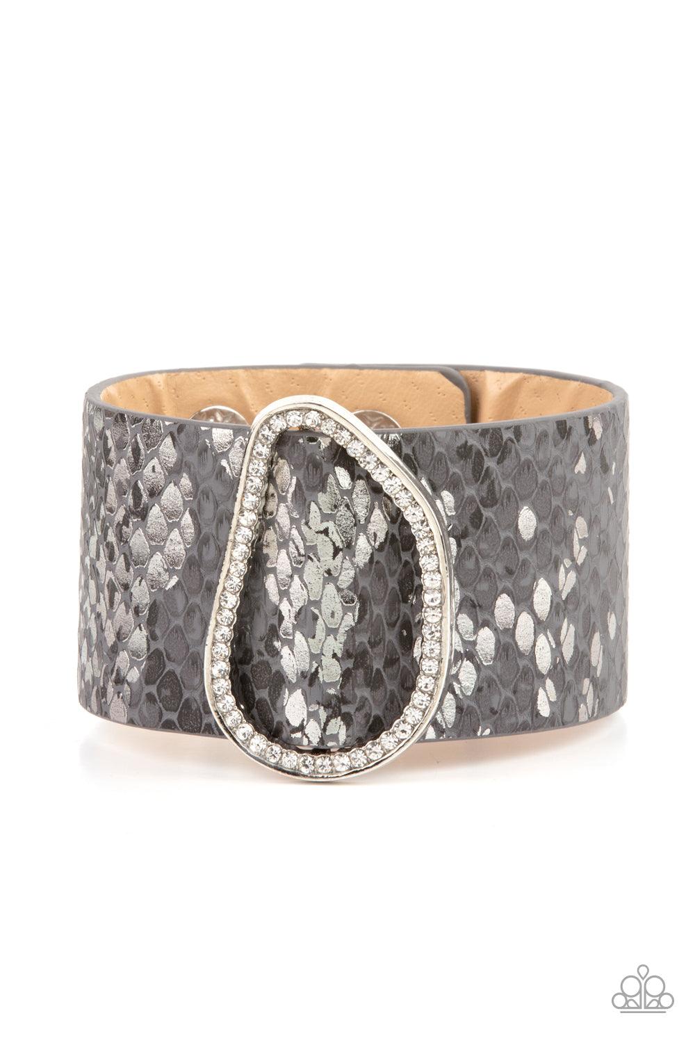 Paparazzi Accessories HISS-tory In The Making - Silver Encrusted with glassy white rhinestones, an asymmetrical silver fitting glides along a gray leather band adorned in a metallic python print for a wild look. Features an adjustable snap closure. Sold a
