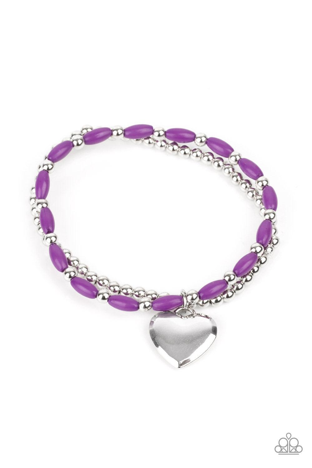 Paparazzi Accessories Candy Gram - Purple A shiny silver heart dangles from a strand of playful purple beads. It is paired with a strand of round silver beads threaded along a stretchy band for a whimsical charm around the wrist. Sold as one pair of brace