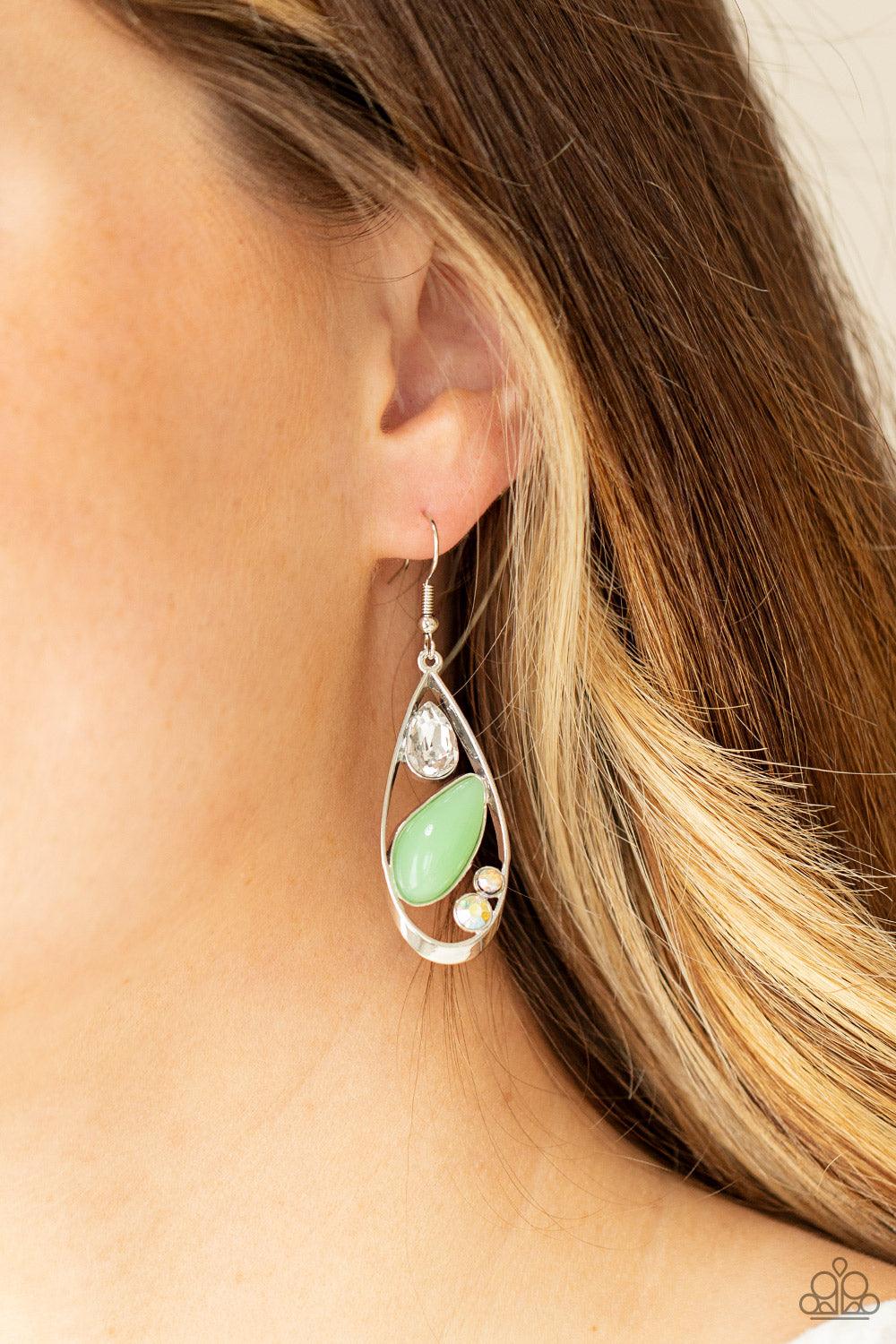 Paparazzi Accessories Harmonious Harbors - Green A silver teardrop frame embraces a collection of iridescent rhinestones and a milky Green Ash bead that is reminiscent of seashore finds. Earring attaches to a standard fishhook fitting. Sold as one pair of