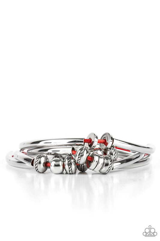 Paparazzi Accessories We Aim To Please - Red Multiple strands of red cord are fitted with long, curved cylinders that meet in the middle. The sliding bars are separated by small antiqued silver loops that mimic pipe fittings, making this a perfect additio