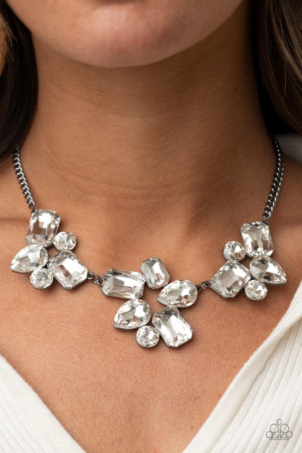 Paparazzi Accessories Galactic Goddess - Black An unexpected explosion of oversized round, teardrop, and emerald cut rhinestones cluster into haphazard groupings. The blinding clusters link together, creating a stellar statement piece that sits below the
