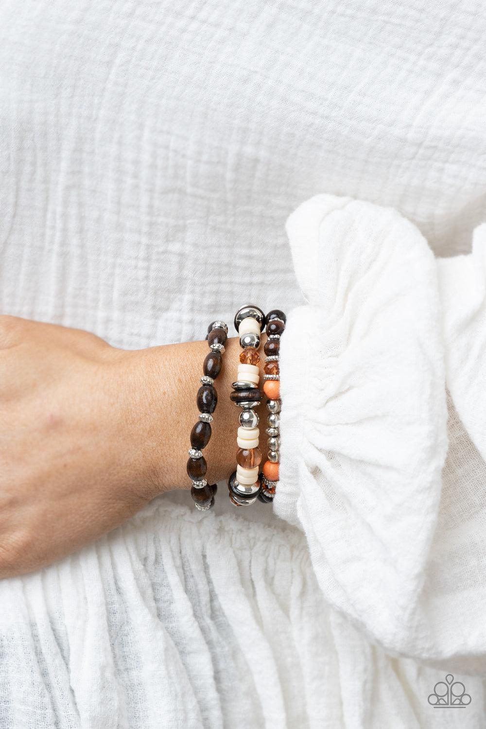 Paparazzi Accessories Belongs In The Wild - Multi A mismatched collection of brown wooden beads, silver accents, orange stones, Buttercream discs, and glassy Desert Mist beads are threaded along stretchy bands, creating colorful layers around the wrist. S