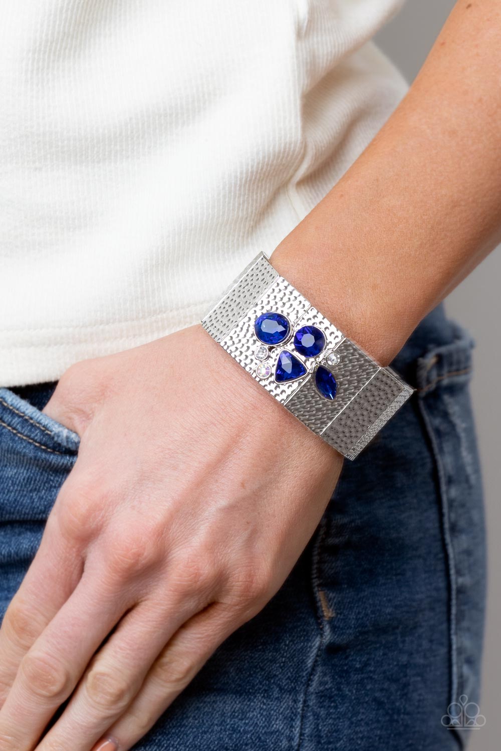 Paparazzi Accessories Flickering Fortune - Blue Hammered in gritty shimmer, rustic, rectangular, silver frames are threaded along stretchy bands that wrap around the wrist. Mismatched white, iridescent, and blue rhinestones cluster on the front and back o