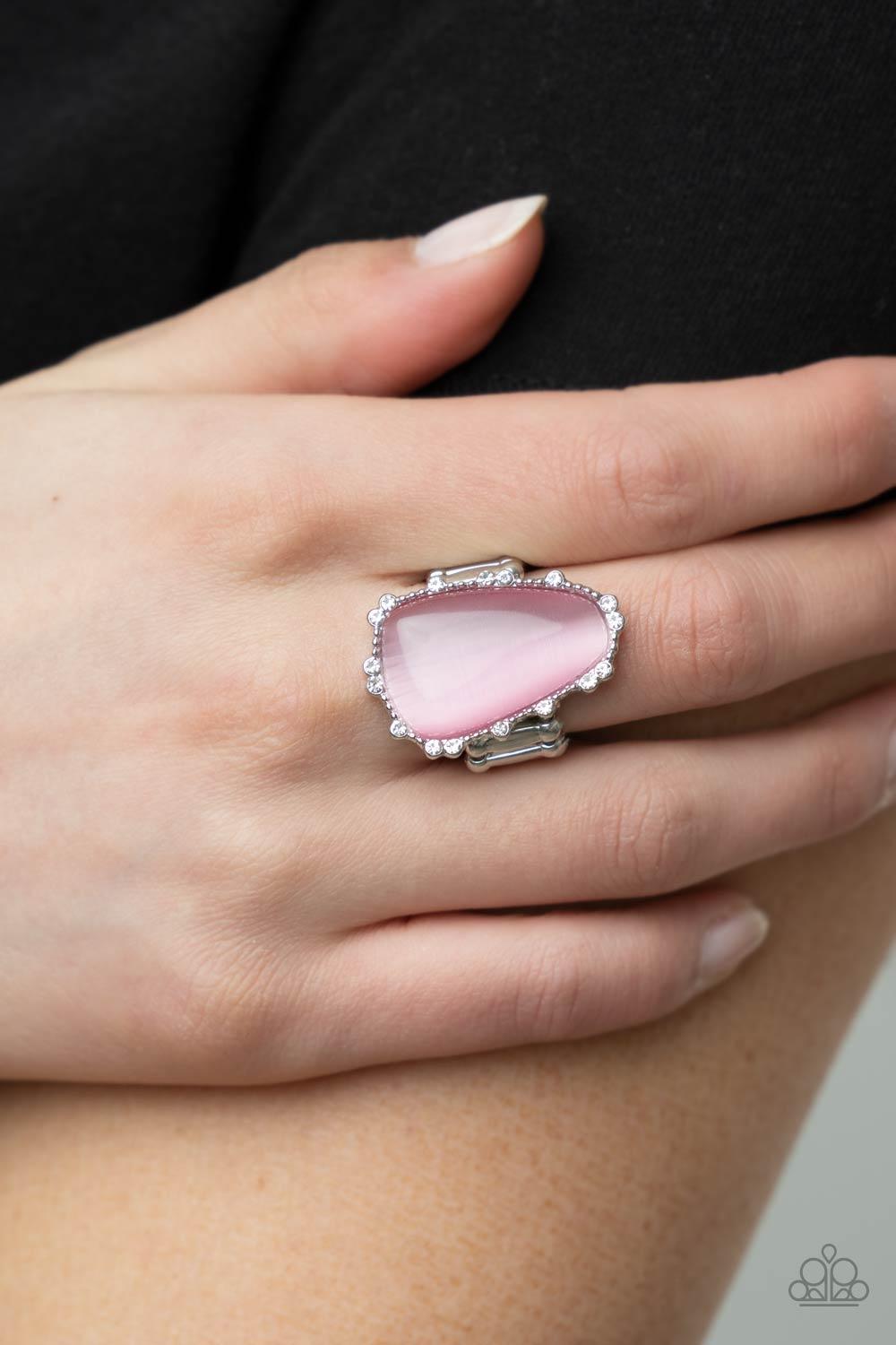 Paparazzi Accessories Newport Nouveau - Pink A tranquil asymmetrical pink cat's eye stone is encased in a delicately dotted shimmery silver frame. Dainty sparkly white rhinestones surround the oversized stone creating an elegant centerpiece atop the finge