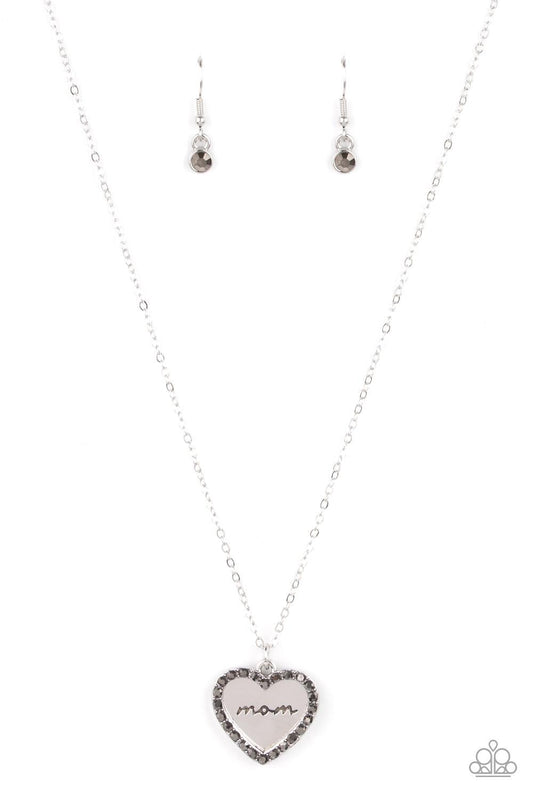 Paparazzi Accessories The Real Boss - Silver Infused with a smoky hematite rhinestone encrusted silver heart, a silver heart shaped pendant is stamped in the word, "Mom," as it swings below the collar, creating a sparkly sentimental statement piece. Featu