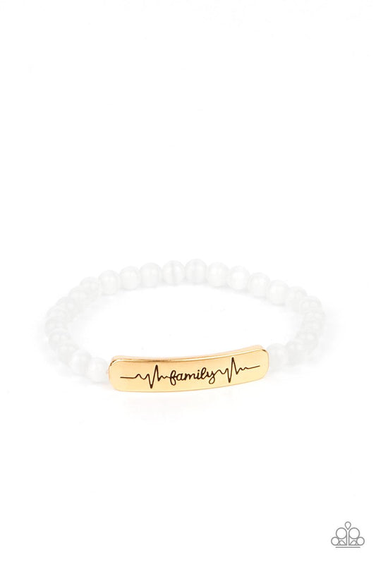 Paparazzi Accessories Family is Forever - Gold Stamped in heartbeats and the word, "Family," a glistening gold plate attaches to a strand of white cat's eye stone beads that are threaded along a stretchy band, creating a whimsically sentimental centerpiec