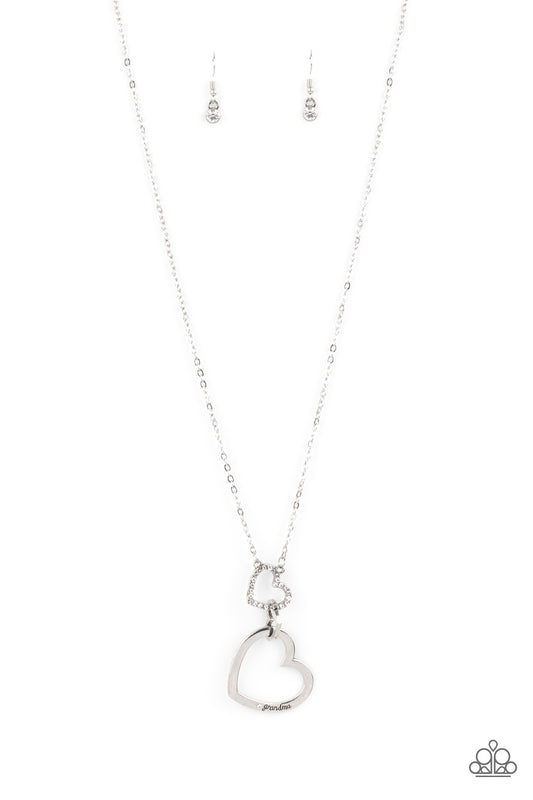 Paparazzi Accessories Grandma Glow - White A silver heart engraved with the word "Grandma," dangles from two smaller hearts at the bottom of a lengthened silver chain. The first heart is accented with sparkly white rhinestones creating an affectionately s