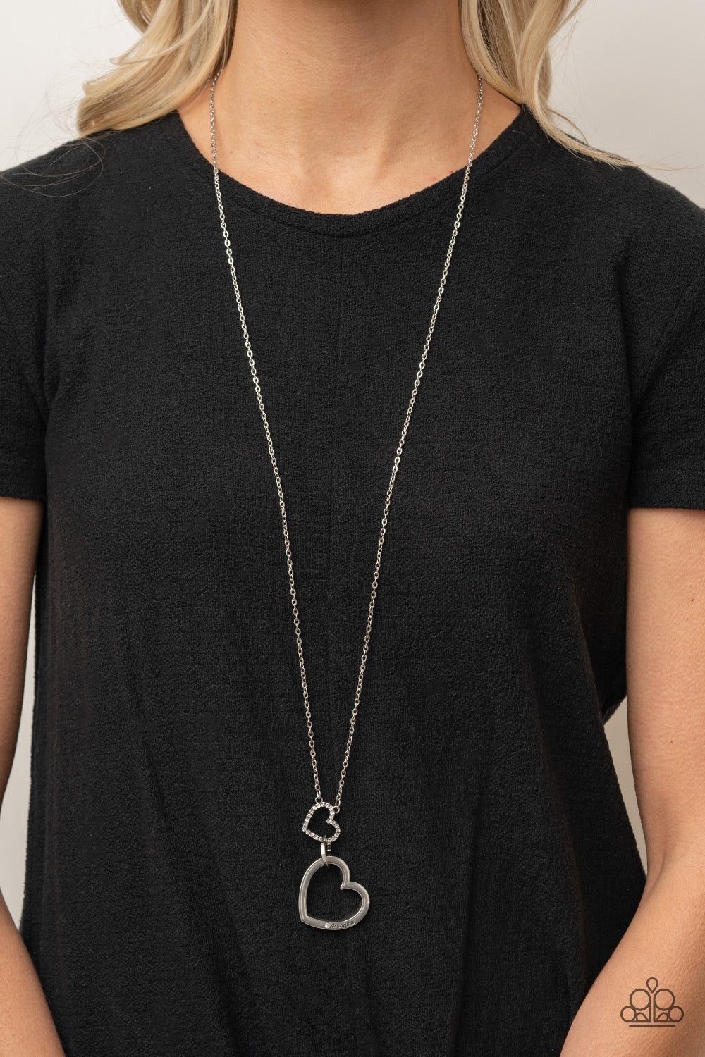 Paparazzi Accessories Grandma Glow - White A silver heart engraved with the word "Grandma," dangles from two smaller hearts at the bottom of a lengthened silver chain. The first heart is accented with sparkly white rhinestones creating an affectionately s