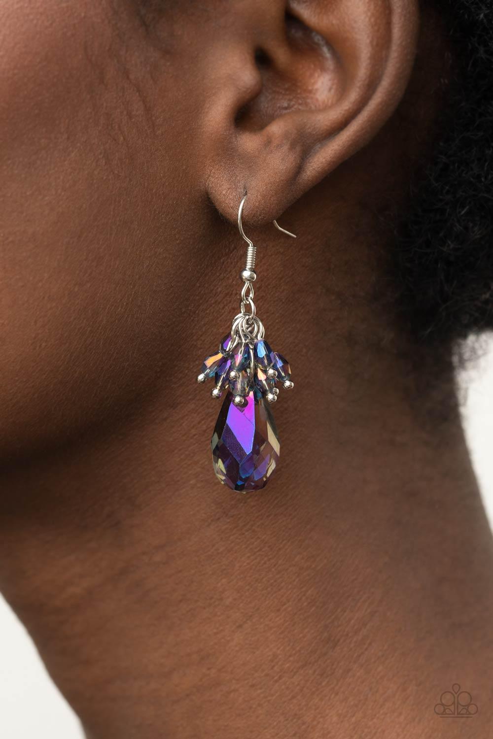 Paparazzi Accessories Well Versed in Sparkle - Purple A cluster of dainty oil spill iridescent beads delicately overlap atop an oversized smoky purple iridescent teardrop gem, creating a sparkly chandelier. Earring attaches to a standard fishhook fitting.