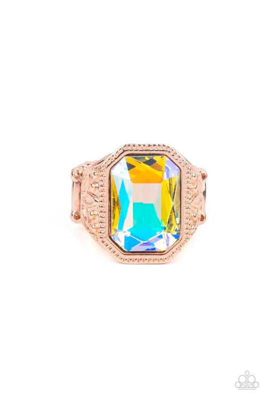 Paparazzi Accessories Galaxy Goddess - Rose Gold Featuring a dramatic UV shimmer, an oversized emerald cut gem is pressed into the center of a thick rose gold frame embossed in leafy patterns for a stellar statement atop the finger. Features a stretchy ba