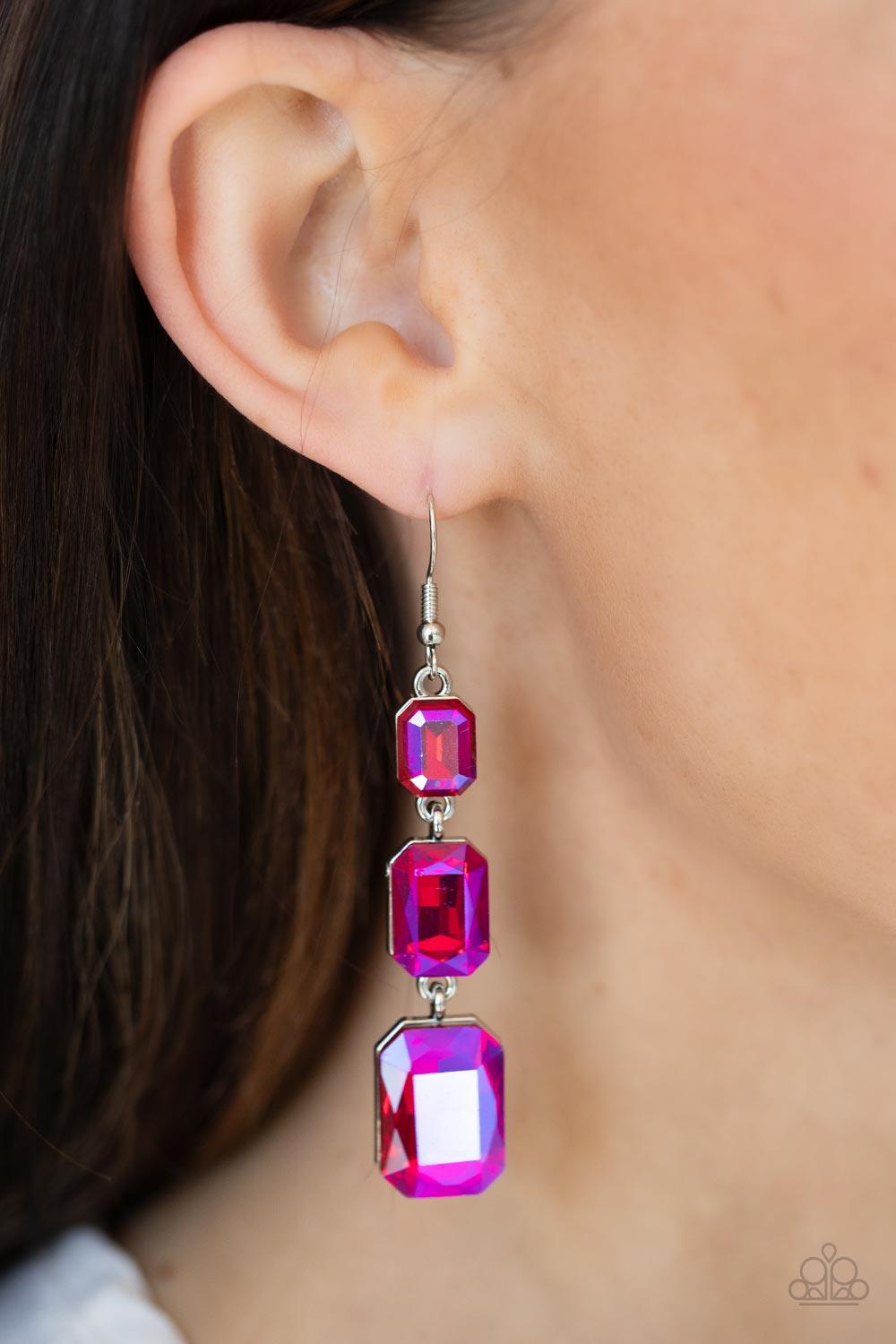 Paparazzi Accessories Cosmic Red Carpet - Pink Featuring a dazzling pink UV shimmer, a trio of emerald-cut gems in graduating sizes is linked one below the other for a dramatic red carpet finish. Earring attaches to a standard fishhook fitting. Sold as on