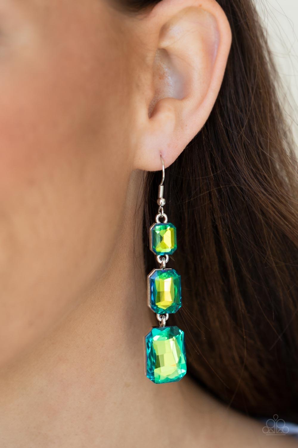 Paparazzi Accessories Cosmic Red Carpet - Green Featuring a dazzling green and gold UV shimmer, a trio of emerald-cut gems in graduating sizes is linked one below the other for a dramatic red carpet finish. Earring attaches to a standard fishhook fitting.