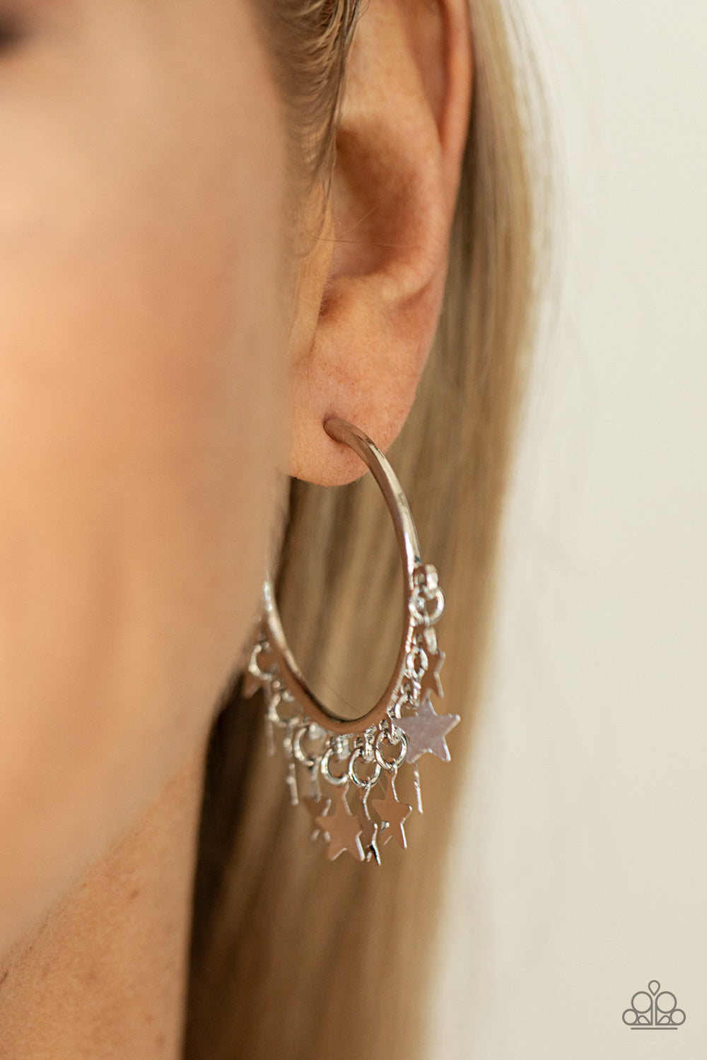 Paparazzi Accessories Happy Independence Day - Silver A shiny collection of silver star charms trickles from the bottom of a classic silver hoop, creating a stellar fringe. Earring attaches to a standard post fitting. Hoop measures approximately 1 1/4" in