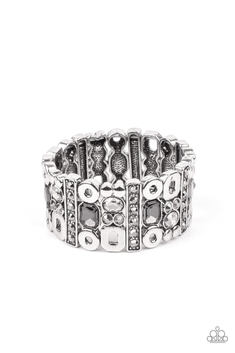 Paparazzi Accessories Dynamically Diverse - Silver Infused with flat silver studs and geometric silver accents, a mismatched assortment of oval, round, and emerald style hematite and smoky rhinestones coalesce into edgy frames along a stretchy band for an