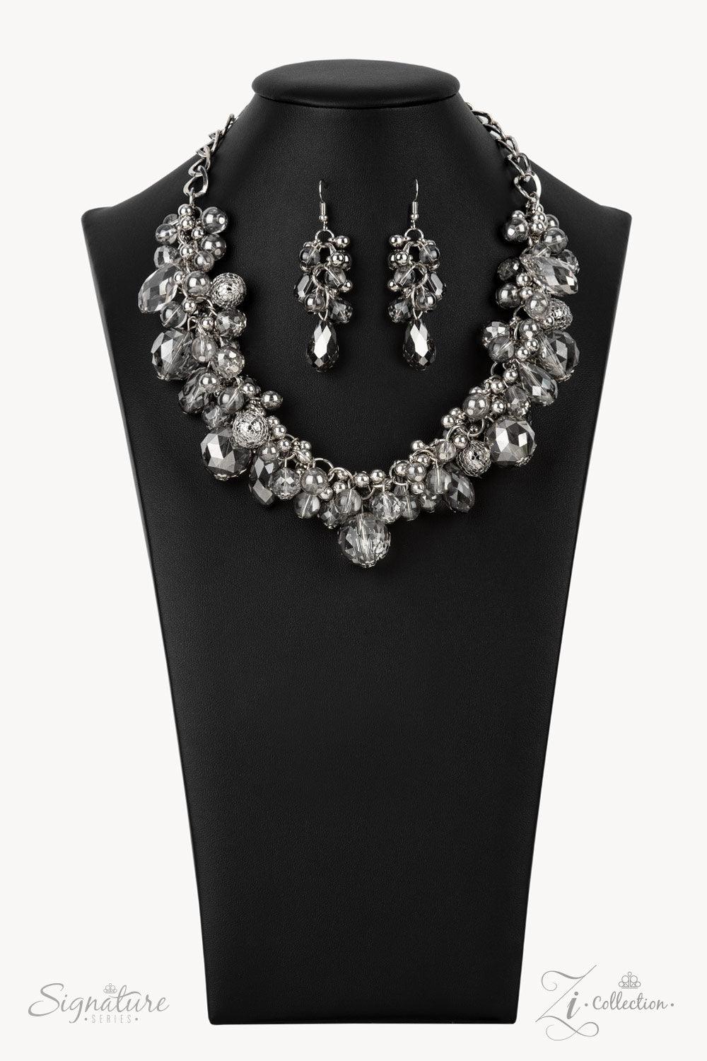 Paparazzi Accessories The Tommie Elegantly enhanced with classic silver and silvery wire mesh beads, a glassy glamorous collection of majestically mismatched smoky crystal-like beads capriciously cluster along a bold silver chain below the collar. Each fa