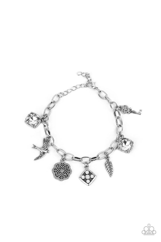 Paparazzi Accessories Fancifully Flighty - White White gems, a floral medallion, a bird in flight, and a fluttering feather coalesce into a whimsical charm bracelet as they dangle from a delicate silver chain around the wrist. Features an adjustable clasp