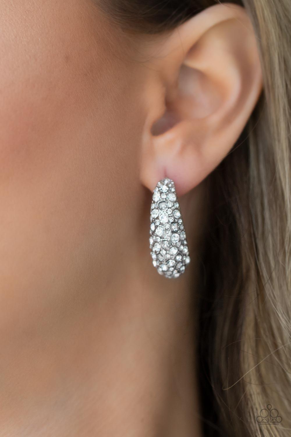 Paparazzi Accessories Glamorously Glimmering - White Featuring a beveled surface, a thick hammered silver hoop is haphazardly encrusted in round and square white rhinestones for a glamorously glittery finish. Earring attaches to a standard post fitting. H