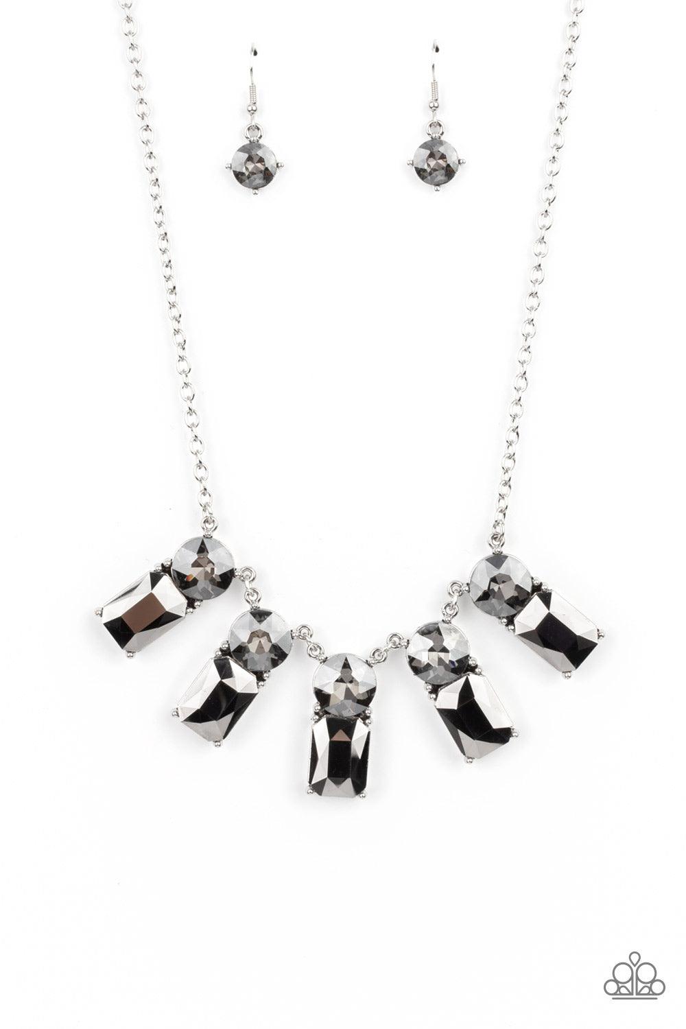 Paparazzi Accessories Celestial Royal - Silver Featuring classic pronged fittings, a dramatic collection of oversized smoky rhinestones and emerald cut hematite gems fan out below the collar for an outrageous sparkle. Features an adjustable clasp closure.