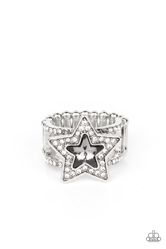 Paparazzi Accessories One Nation Under Sparkle - Silver A star shaped smoky gem is pressed into the center of a silver star dotted in blinding white rhinestones, creating a stellar centerpiece atop two white rhinestone encrusted silver bands. Features a s