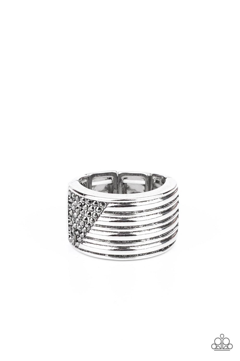 Paparazzi Accessories Legendary Lineup - Silver Engraved in linear patterns, the corner of a thick silver band has been chiseled away and encrusted in dainty rows of hematite rhinestones for a standout finish. Features a stretchy band for a flexible fit.