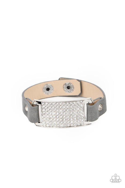 Paparazzi Accessories Urban Rivalry - Silver Gray leather bands are looped through the ends of a white rhinestone embellished silver frame and studded in place with glitzy white rhinestone studs, creating a glamorous centerpiece around the wrist. Features