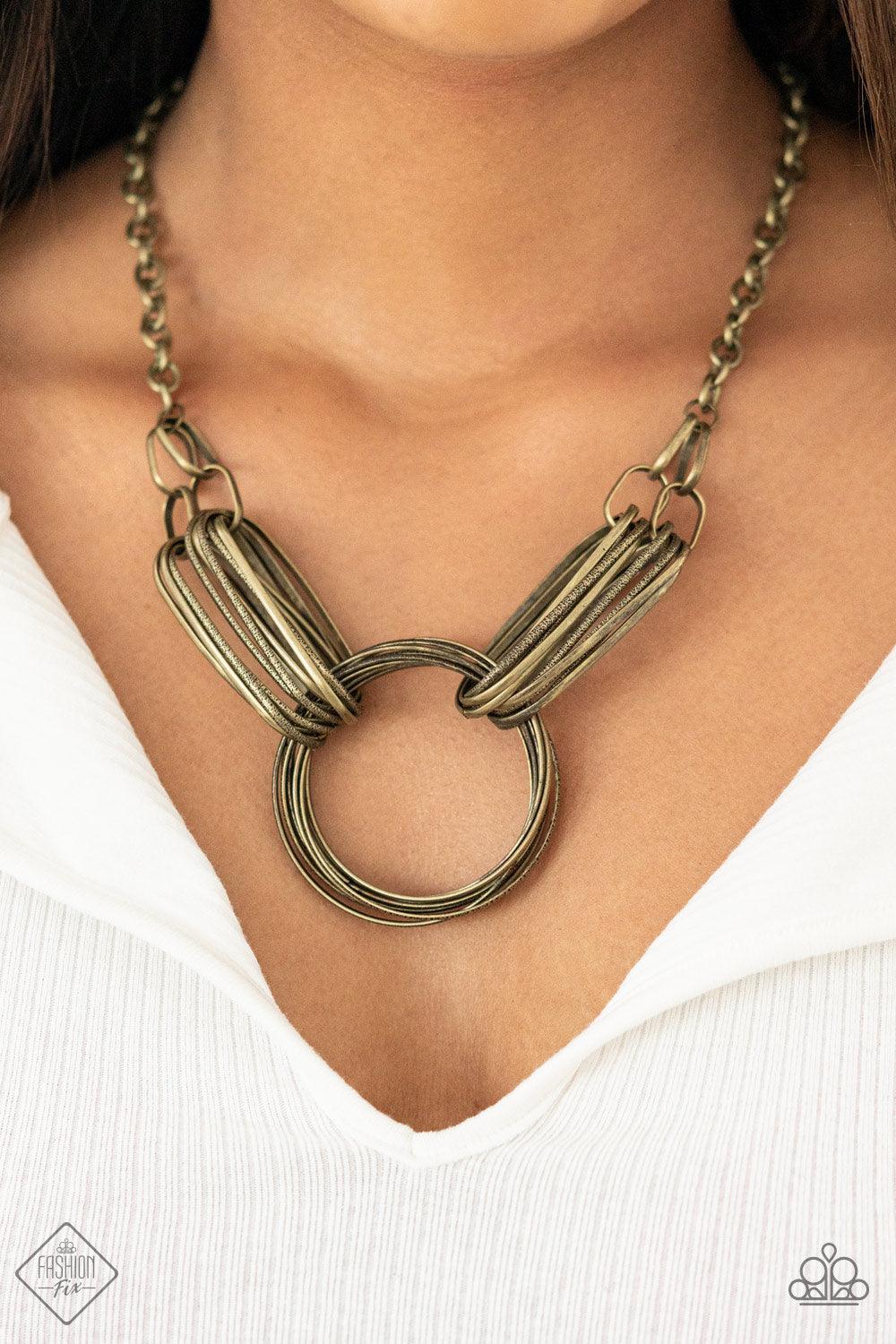 Paparazzi Accessories Lip Sync Links - Brass Layers of oblong brass links attach to a collection of oversized antiqued brass rings creating a dramatic industrial centerpiece. Attached to a brass chain, the rustic links create an unconventionally edgy stat