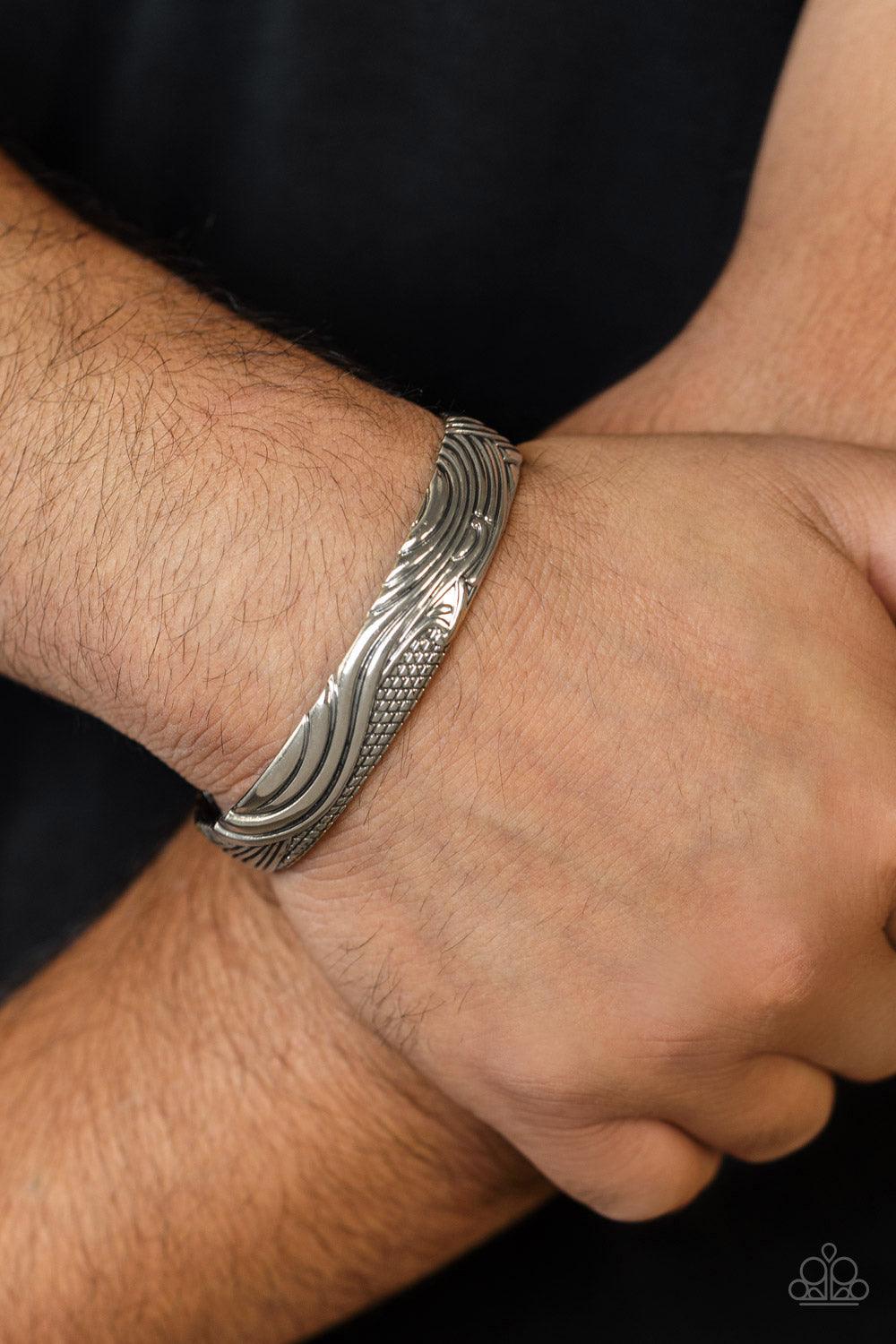 Paparazzi Accessories Tidal Trek - Silver Billowing with wave-like and sections of geometric texture, an embossed silver cuff curls around the wrist for a seasonal look. Sold as one individual bracelet. Bracelets