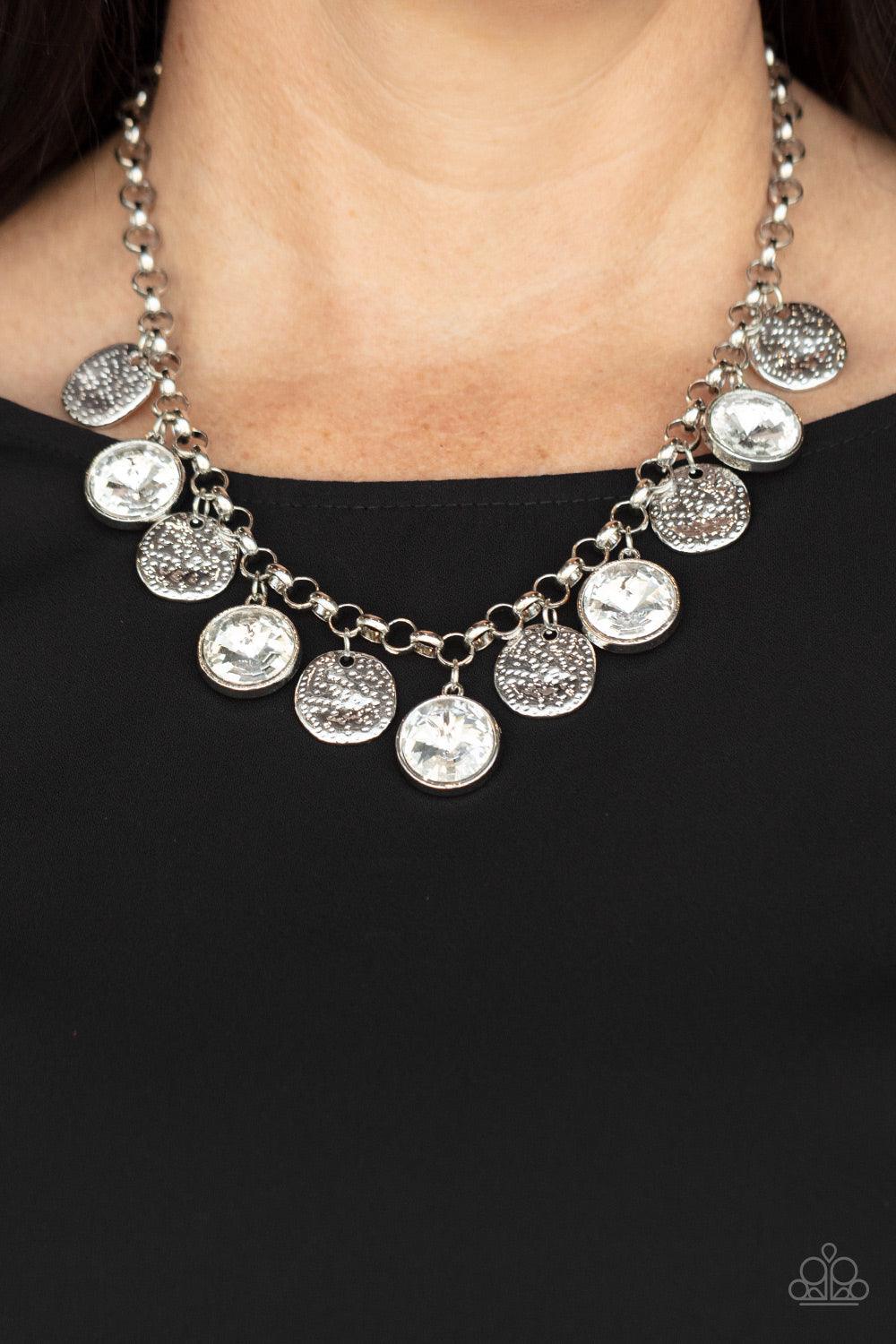 Paparazzi Accessories Spot On Sparkle - White A blinding collection of hammered silver discs and oversized white gems swing from the bottom of a bold silver chain, creating noise-making sparkle below the collar. Features an adjustable clasp closure. Sold