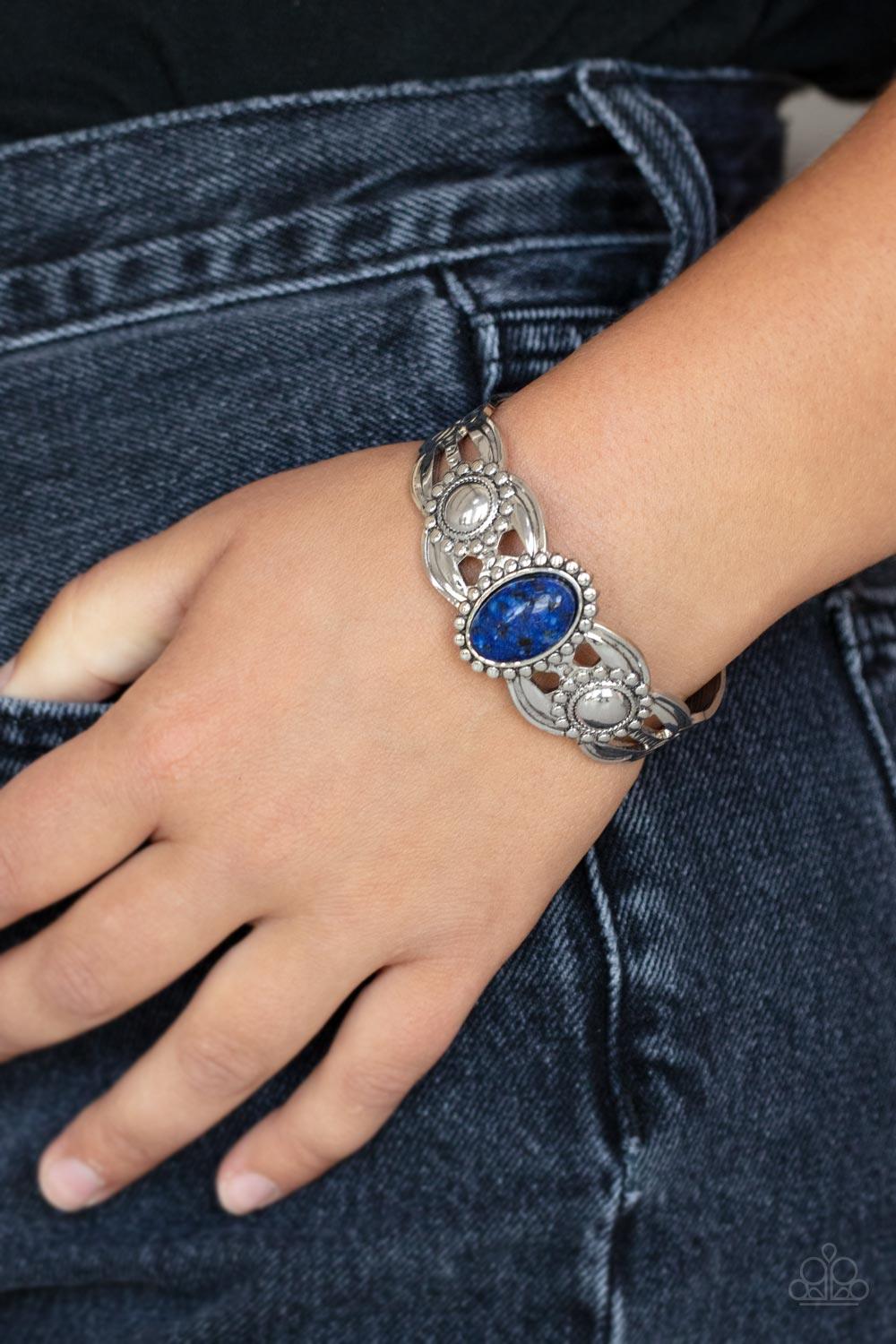 Paparazzi Accessories Solar Solstice - Blue An oval blue stone is pressed into the center of a studded silver frame atop an airy silver cuff embellished in studded sun-like frames for an earthy pop of seasonal color around the wrist. Sold as one individua