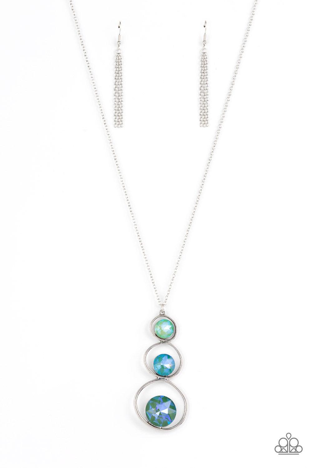 Paparazzi Accessories Celestial Courtier - Green A sparkly ombré of opalescent green gems adorn the bottoms of three silver hoops that gradually increase in size as they stack into an asymmetrical pendant. The glowing pendant swings from the bottom of a l