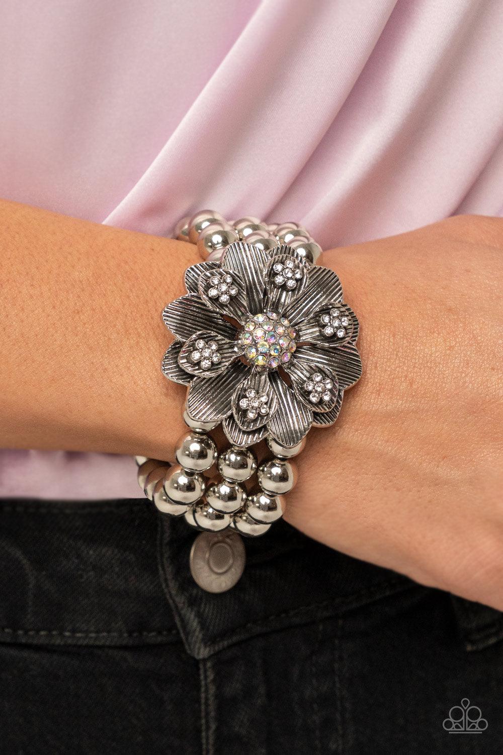 Paparazzi Accessories Botanical Bravado - Multi A daring oversized silver flower is composed of petals lined in antiqued silver and dotted with glistening dainty white rhinestones. A sphere of dainty iridescent rhinestones creates the center of the flower
