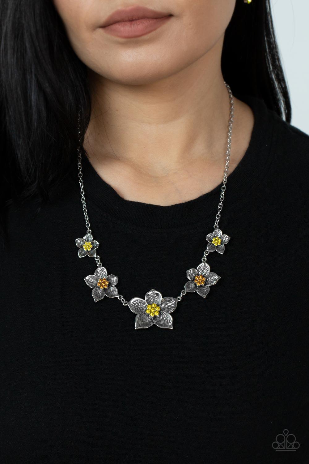 Paparazzi Accessories Wallflower Wonderland - Yellow Gradually increasing in size, textured silver floral frames featuring yellow and orange rhinestone encrusted centers delicately alternate below the collar for a fabulously floral fashion. Features an ad