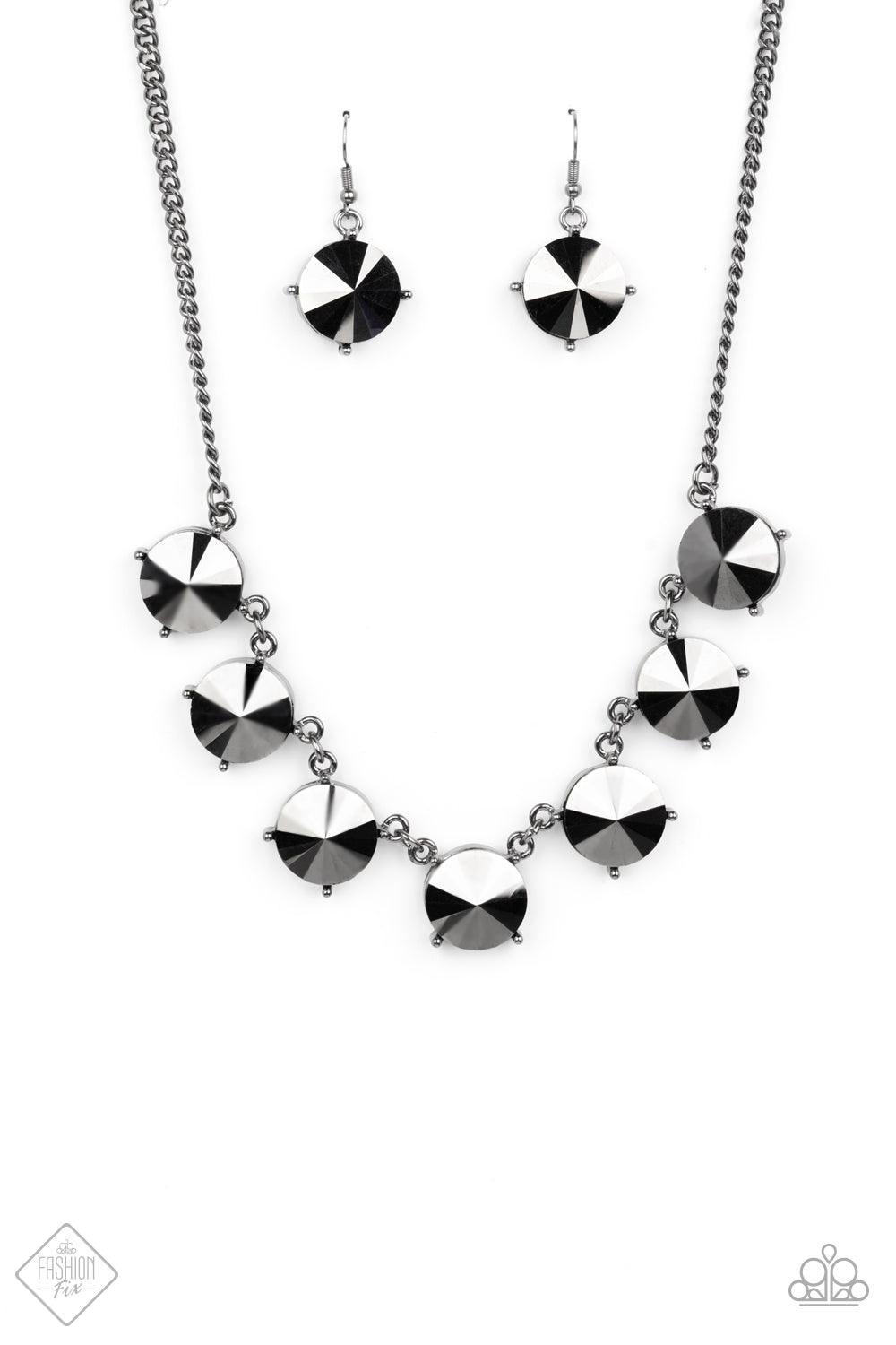 Paparazzi Accessories The SHOWCASE Must Go On - Black Attached to glistening gunmetal chains, a dramatic collection of oversized hematite rhinestones boldly links into a smoldering statement piece below the collar. Features an adjustable clasp closure. So