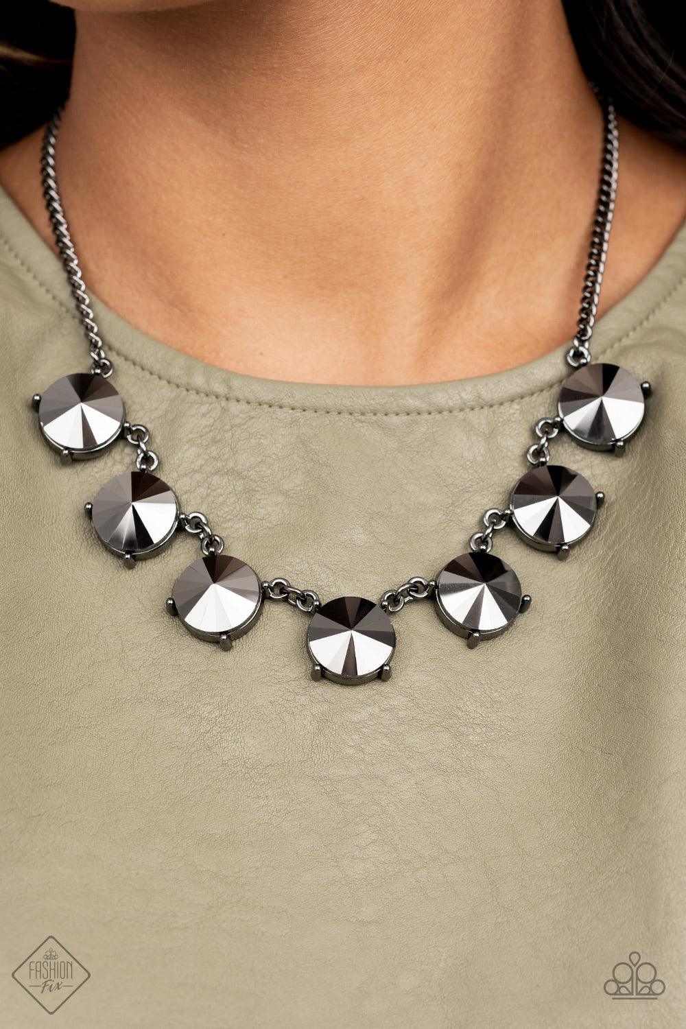 Paparazzi Accessories The SHOWCASE Must Go On - Black Attached to glistening gunmetal chains, a dramatic collection of oversized hematite rhinestones boldly links into a smoldering statement piece below the collar. Features an adjustable clasp closure. So
