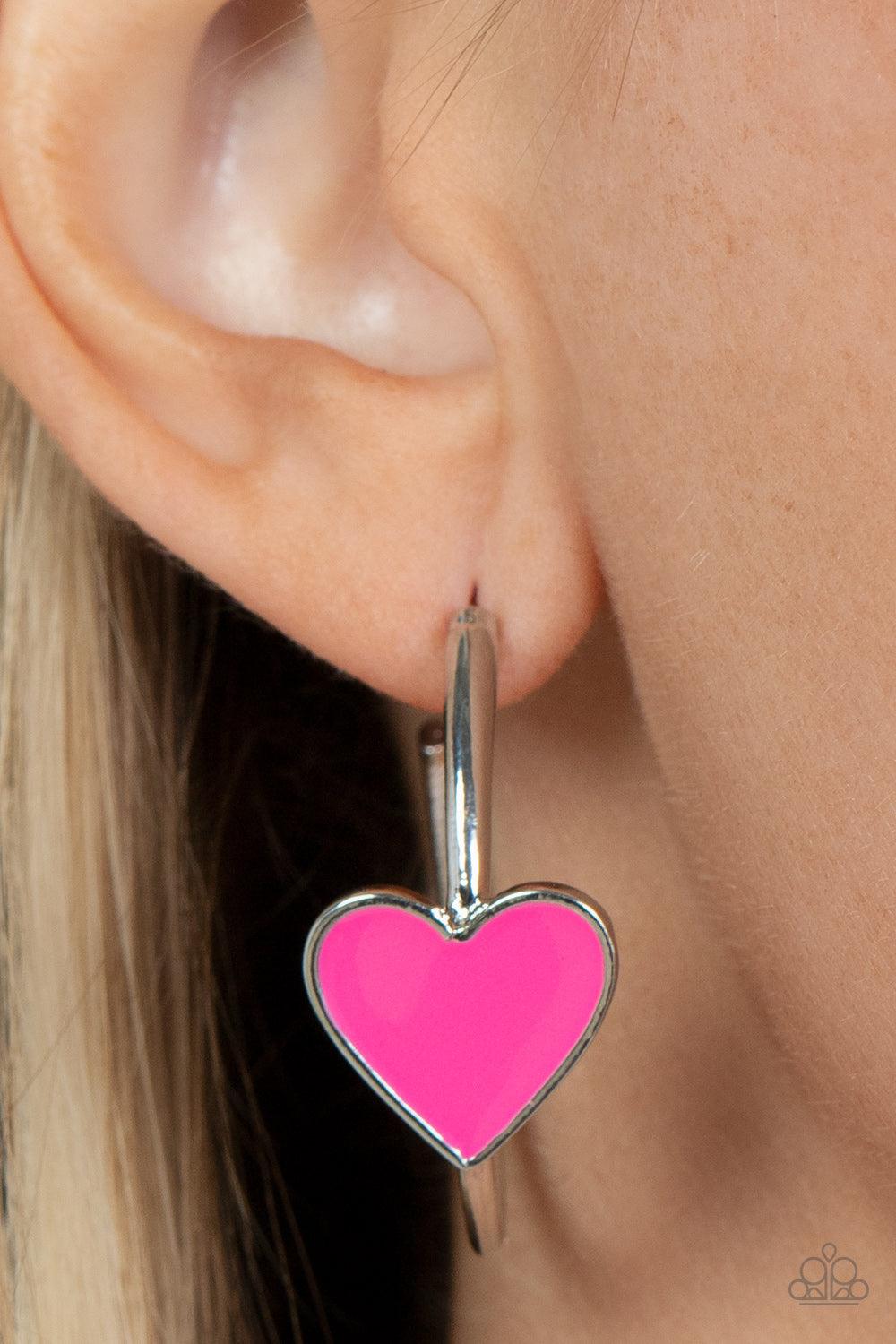 Paparazzi Accessories Kiss Up - Pink A charming Fuchsia Fedora heart adorns the front of a classic silver hoop resulting in a whimsical fashion. Earring attaches to a standard post fitting. Hoop measures approximately 1 1/4" in diameter. Sold as one pair