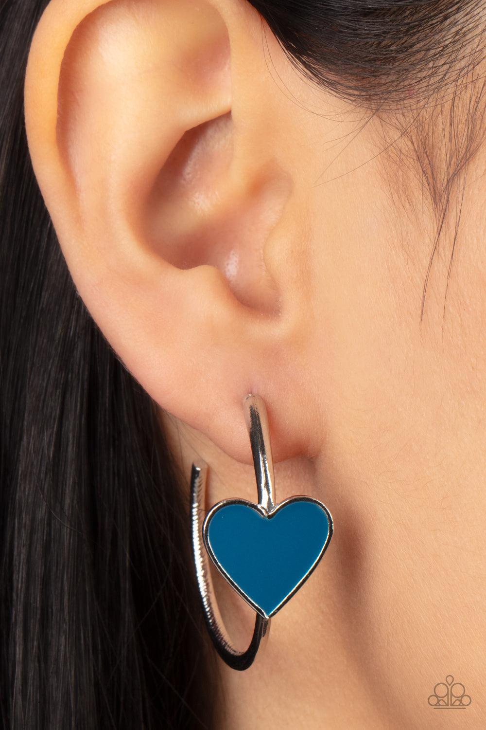 Paparazzi Accessories Kiss Up - Blue A charming Mykonos Blue heart adorns the front of a classic silver hoop resulting in a whimsical fashion. Earring attaches to a standard post fitting. Hoop measures approximately 1 1/4" in diameter. Sold as one pair of