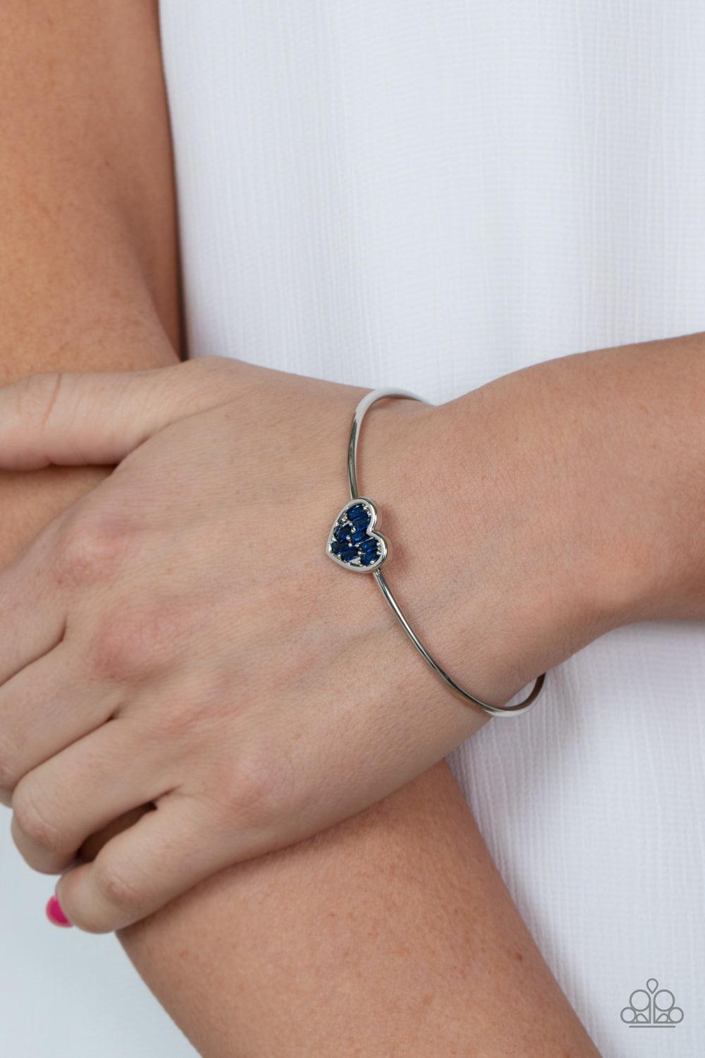 Paparazzi Accessories Heart of Ice - Blue A studded silver heart is encrusted in emerald cut blue rhinestones, creating a flirtatious centerpiece atop a dainty silver cuff. Sold as one individual bracelet. Bracelets