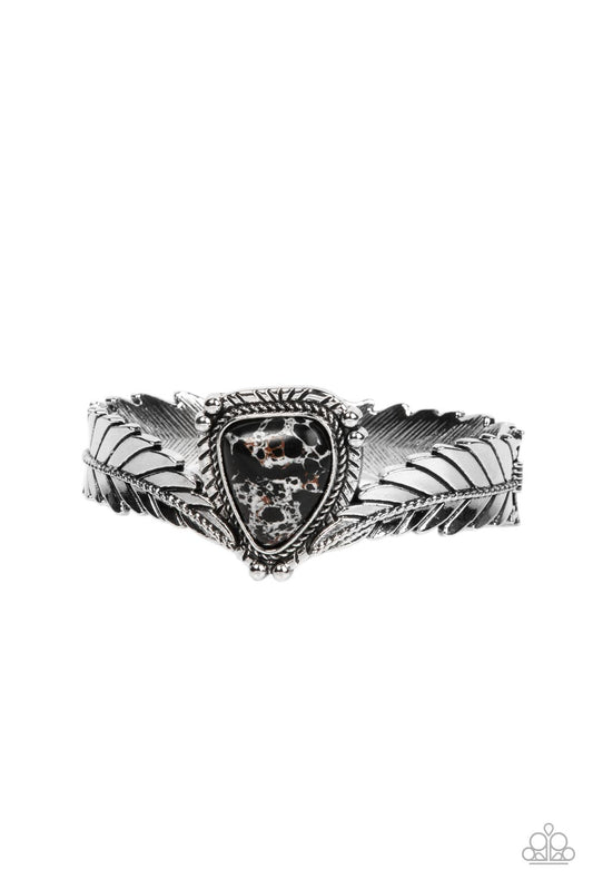 Paparazzi Accessories Desert Roost - Black A twisted metal bar lines the center of an elongated silver feather as it curves into a rustic cuff. Featuring a studded and textured silver frame, an asymmetrical black stone is balanced between the ends of the