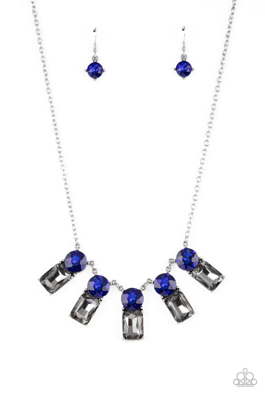 Paparazzi Accessories Celestial Royal - Blue A sparkly row of oversized blue gems regally sit atop emerald cut smoky rhinestone bases as they delicately link along a dainty silver chain below the collar, resulting in a royal glamorous centerpiece. Feature