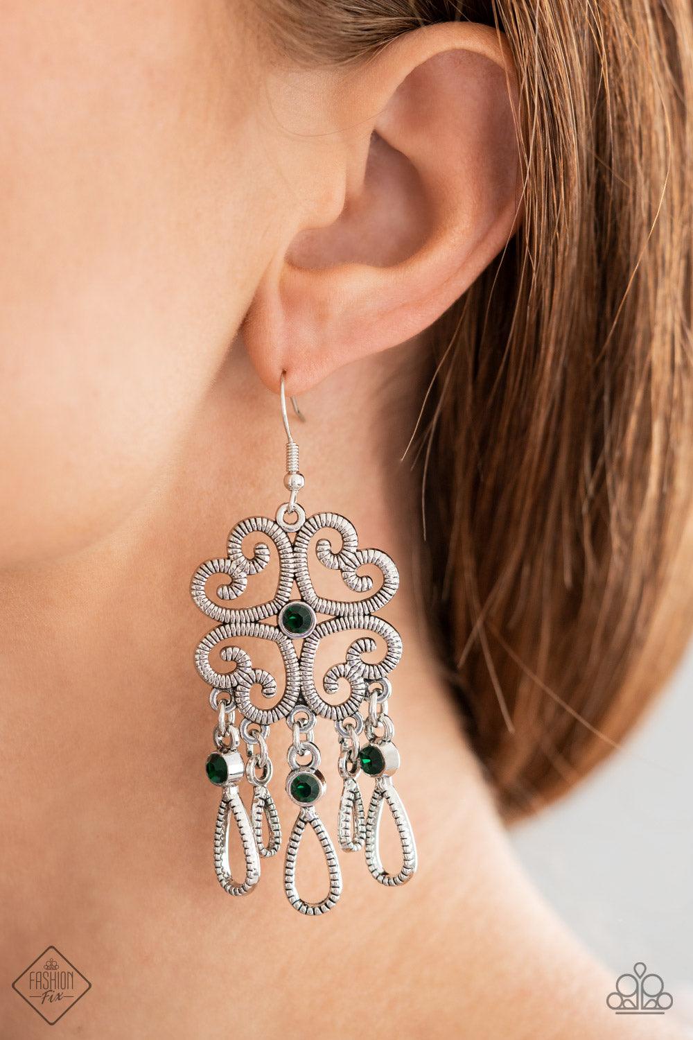 Paparazzi Accessories Majestic Makeover - Green Etched in linear texture, four whimsical hearts coalesce into an airy frame. A dainty emerald rhinestone dots the center while a flirty fringe of teardrop frames adorned with bright emerald rhinestones sways