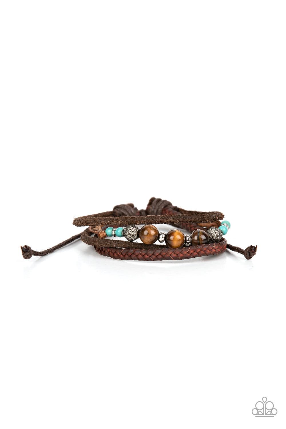 Paparazzi Accessories Tundra Tracker - Blue A strand of Tiger's eye stones, turquoise accents, and decorative silver beads join layers of mismatched leather bands around the wrist for a groovy grounding effect. Features an adjustable sliding knot closure.