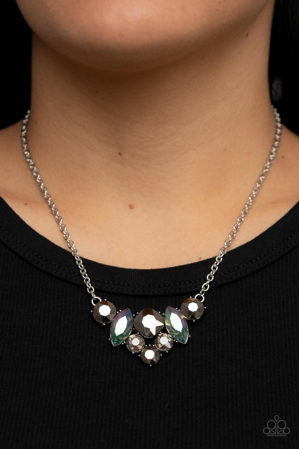 Paparazzi Accessories Lavishly Loaded - Silver A smoldering collection of smoky, iridescent, and hematite gems of various cuts coalesces into a lavish frame at the bottom of a classic silver chain, resulting in a glamorous finish below the collar. Sold as