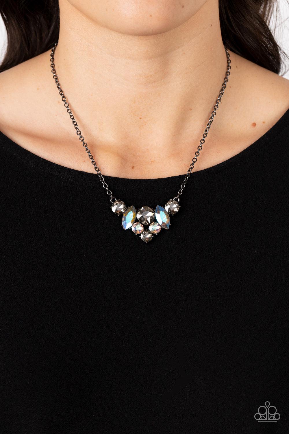 Paparazzi Accessories Lavishly Loaded - Black A smoldering collection of smoky, iridescent, and metallic gems of various cuts coalesces into a lavish frame at the bottom of a classic gunmetal chain, resulting in a glamorous finish below the collar. Sold a
