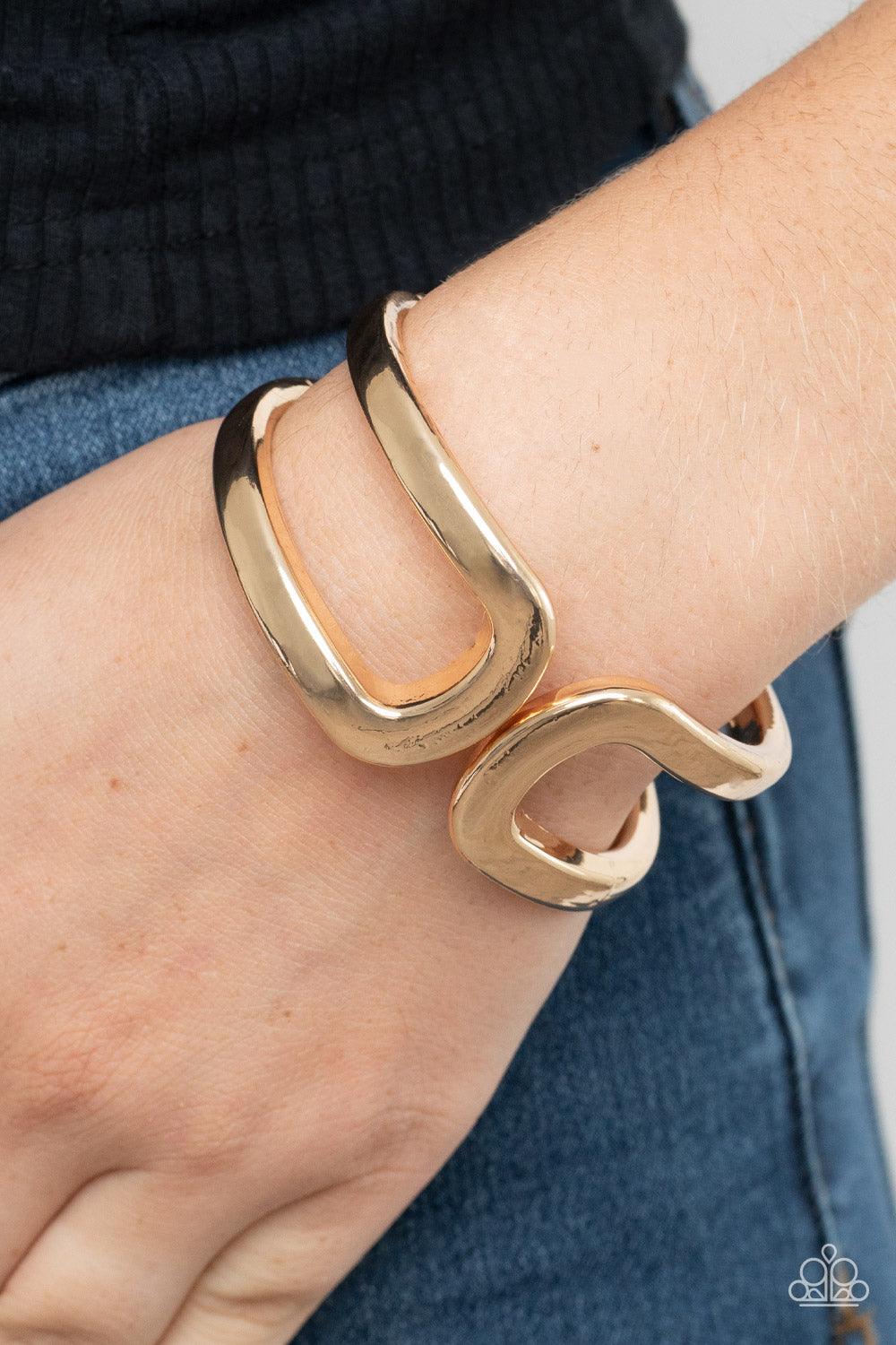 Paparazzi Accessories Industrial Empress - Gold Two oversized gold frames gently curl around the wrist, delicately linking into an impressive cuff-like bangle. Features a hinged closure. Sold as one individual bracelet. Bracelets