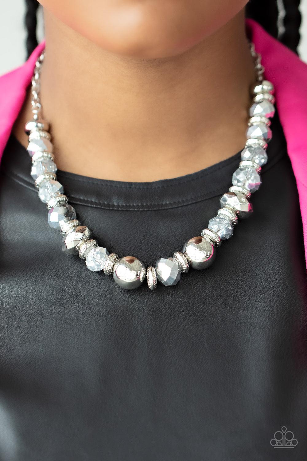 Paparazzi Accessories Interstellar Influencer - Silver A dramatic assortment of oversized silver beads, textured silver rings, and faceted metallic flecked gems delicately glides along an invisible wire below the collar, resulting in a stellar sparkle. Fe