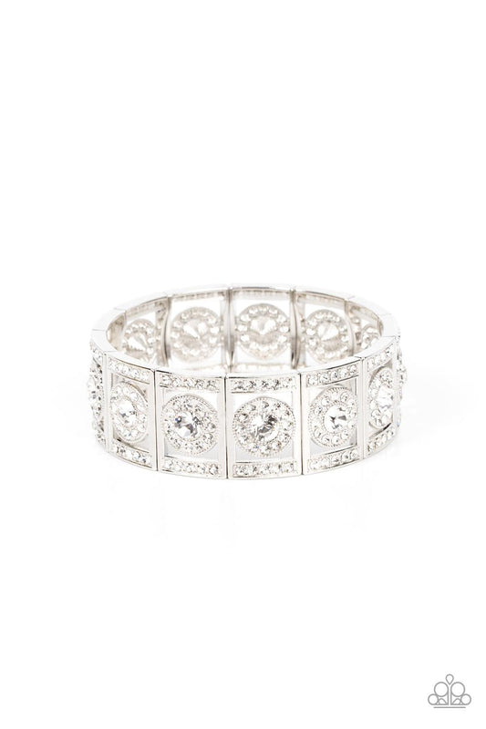 Paparazzi Accessories Ultra Upscale - White A glassy white rhinestone is pressed into a ring of glitzy white rhinestones inside a rectangular silver frame dusted in dazzling white rhinestones. The timeless frames sparkle along stretchy bands around the wr