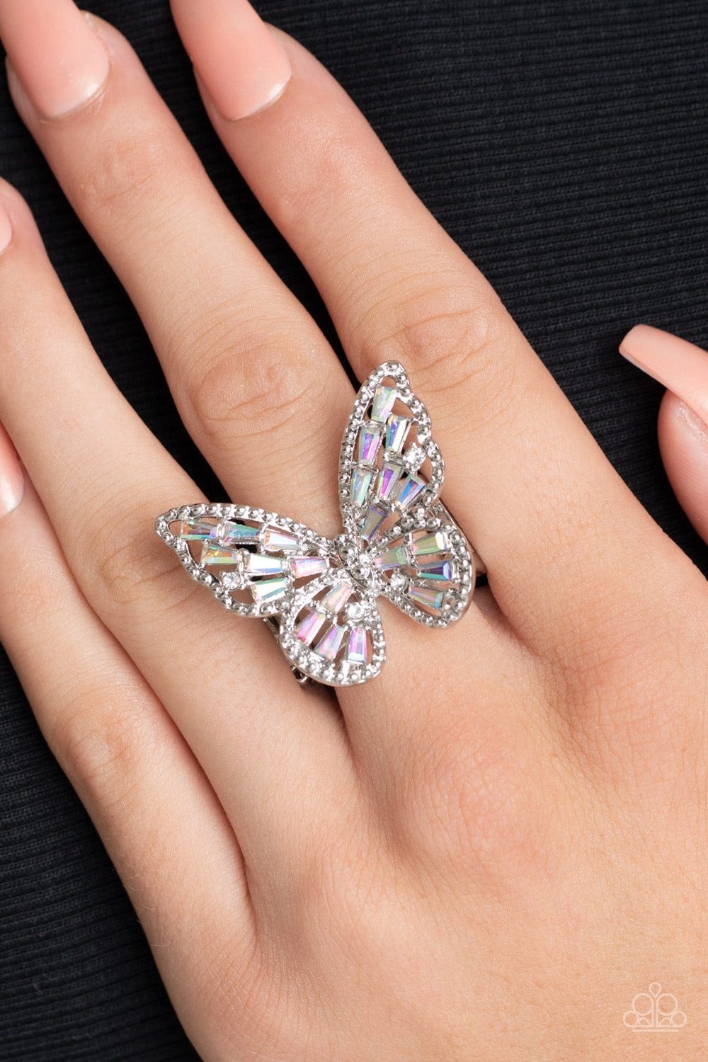 Paparazzi Accessories Bright-Eyed Butterfly - Multi A glitzy collection of emerald cut iridescent rhinestones are sprinkled across the studded wings of a shiny silver butterfly, resulting in a whimsical centerpiece atop the finger. Features a stretchy ban