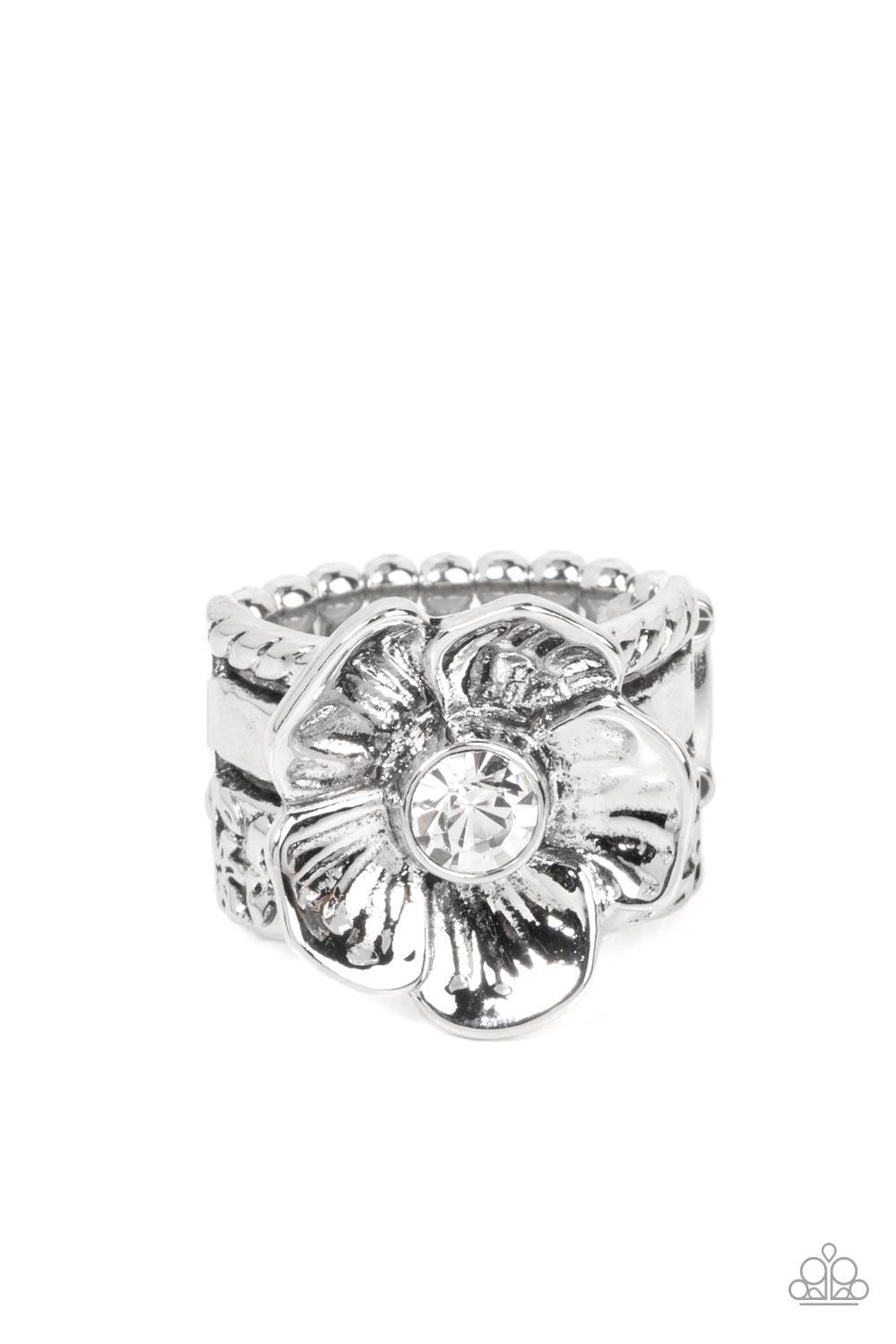 Paparazzi Accessories Prismatically Petunia - White Textured silver petals gently gather around a sparkling white rhinestone center, blooming into a dazzling floral centerpiece atop the finger. Features a stretchy band for a flexible fit. Sold as one indi