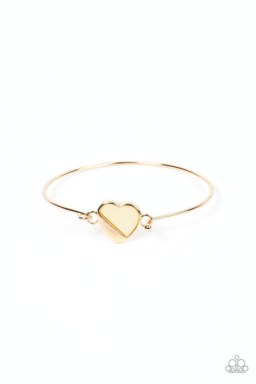 Paparazzi Accessories Hidden Intentions - Gold A glistening gold plate slants across a white shell-like heart charm that delicately hinges to a dainty gold bangle-like bracelet, creating a charming centerpiece around the wrist. Features a barbell closure.