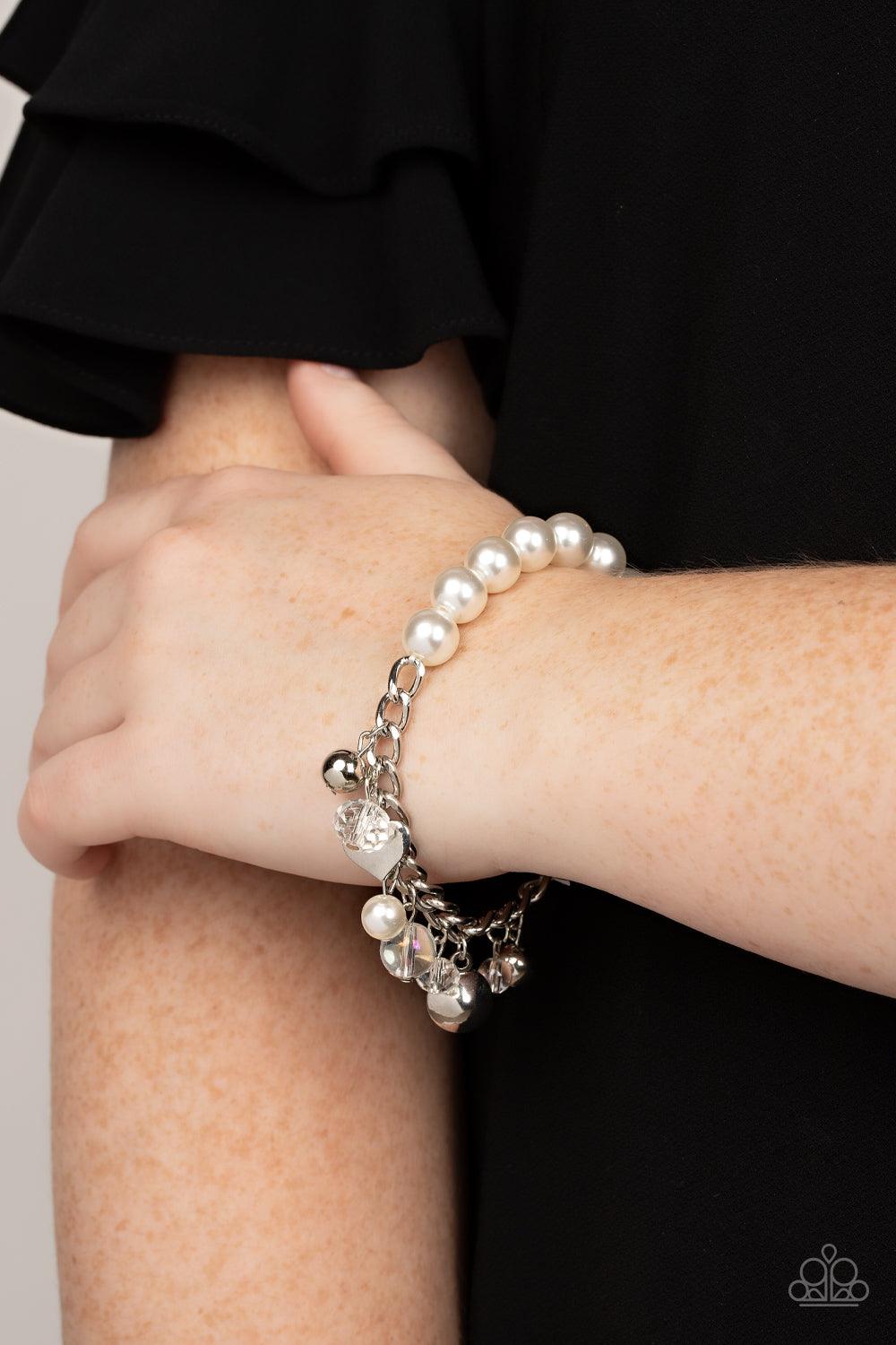 Paparazzi Accessories Adorningly Admirable - White Mismatched silver beads, white pearls, crystal-like accents, gems and heart charms dance from a section of silver chain that attaches to a stretchy band of white pearls around the wrist for a flirtatious